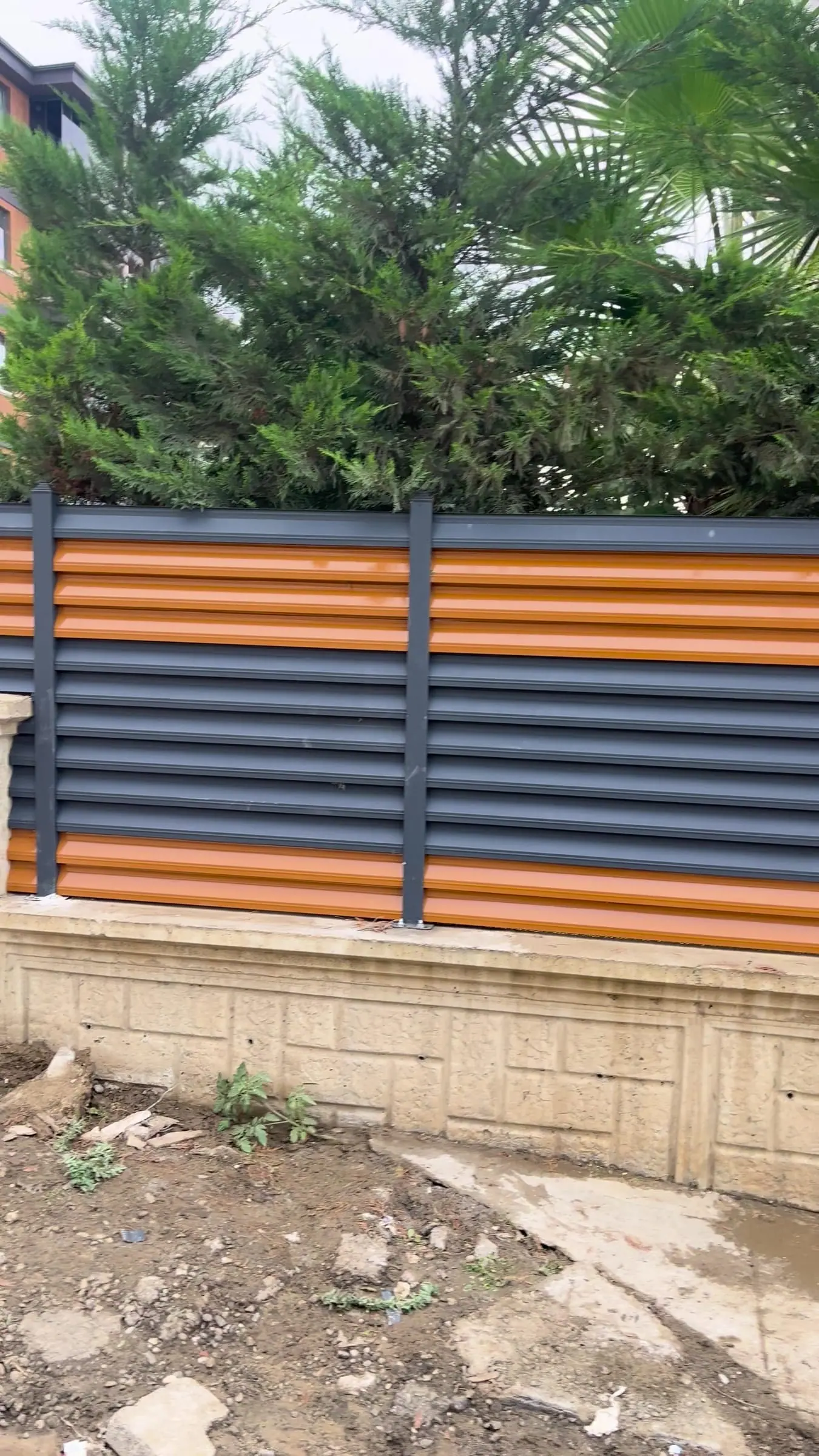 İstinat duvarı üstünde antrasit ve turuncu lamelli panjur çit