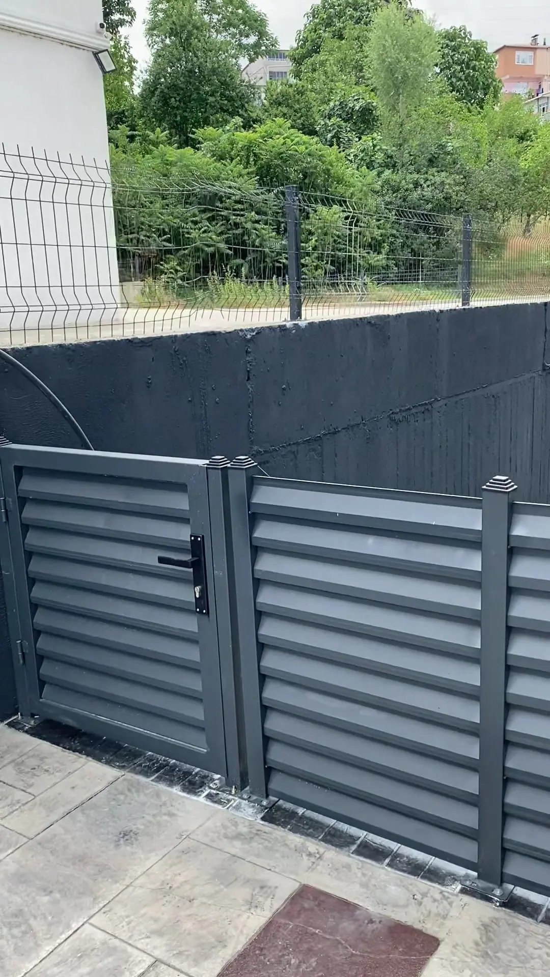 Villa bahçesinde antrasit panjur çit, yaya kapısı ve çelik merdiven