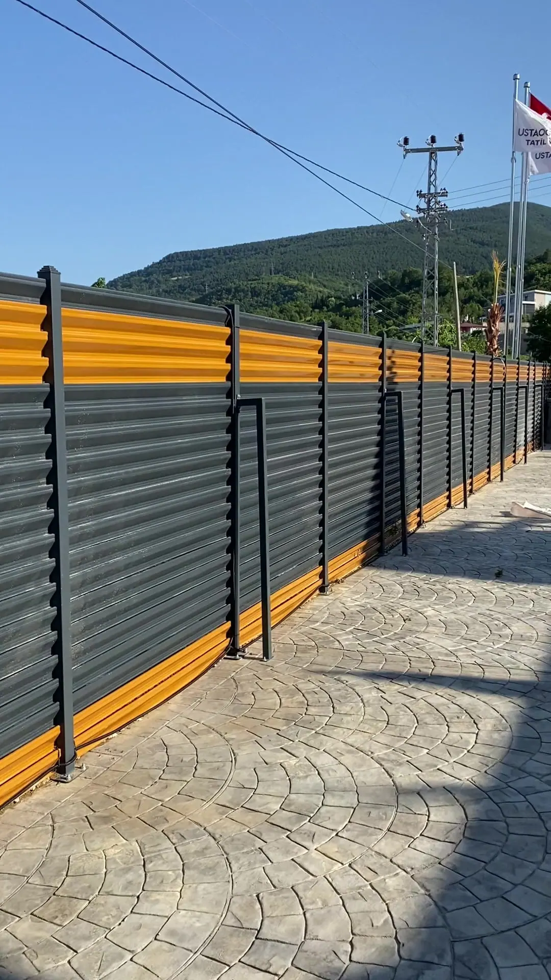 Baskı beton yol boyunca turuncu üst lamelli antrasit panjur çit