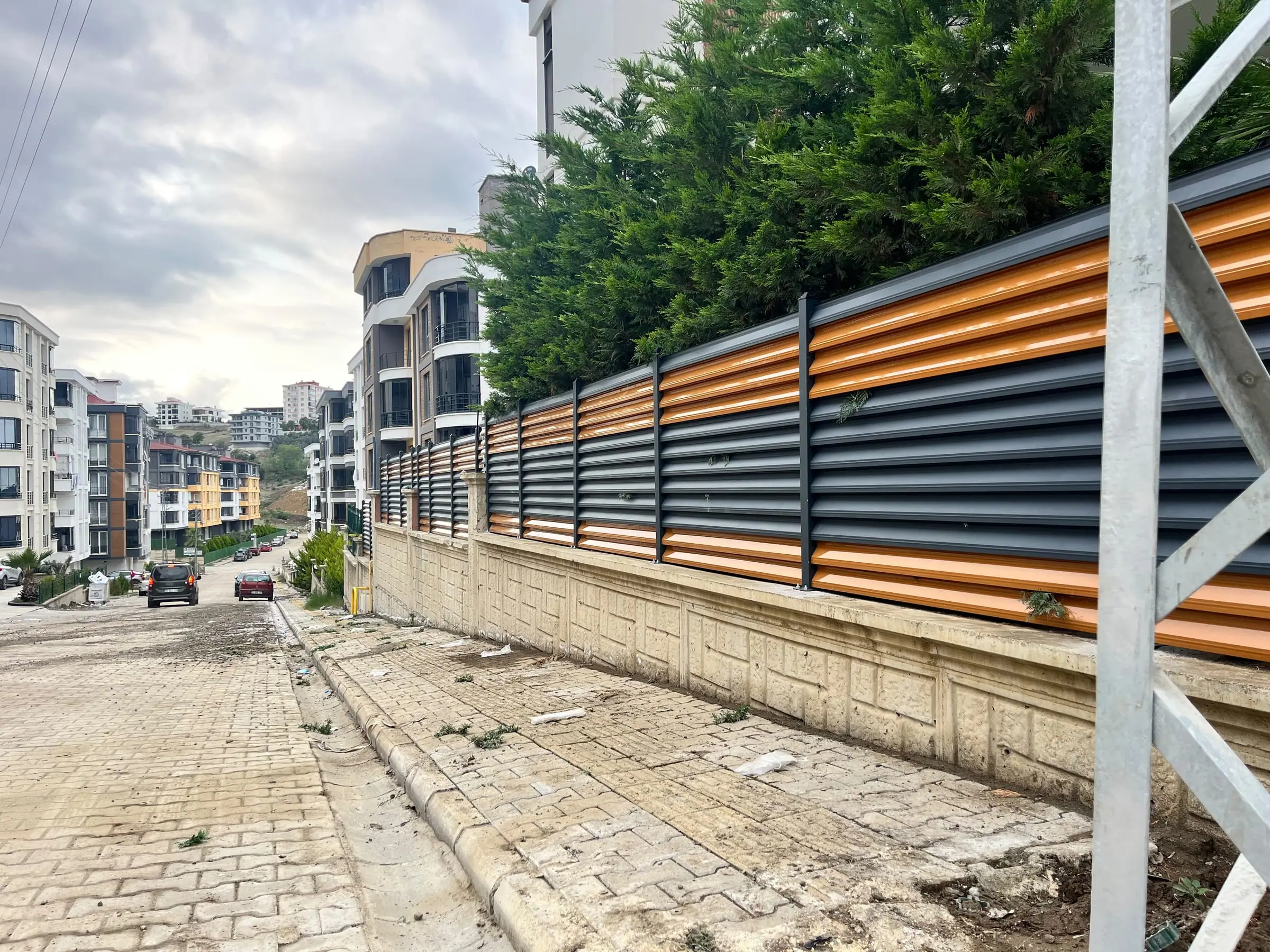 İstinat duvarı üzerinde turuncu ve antrasit panjur çit hattı
